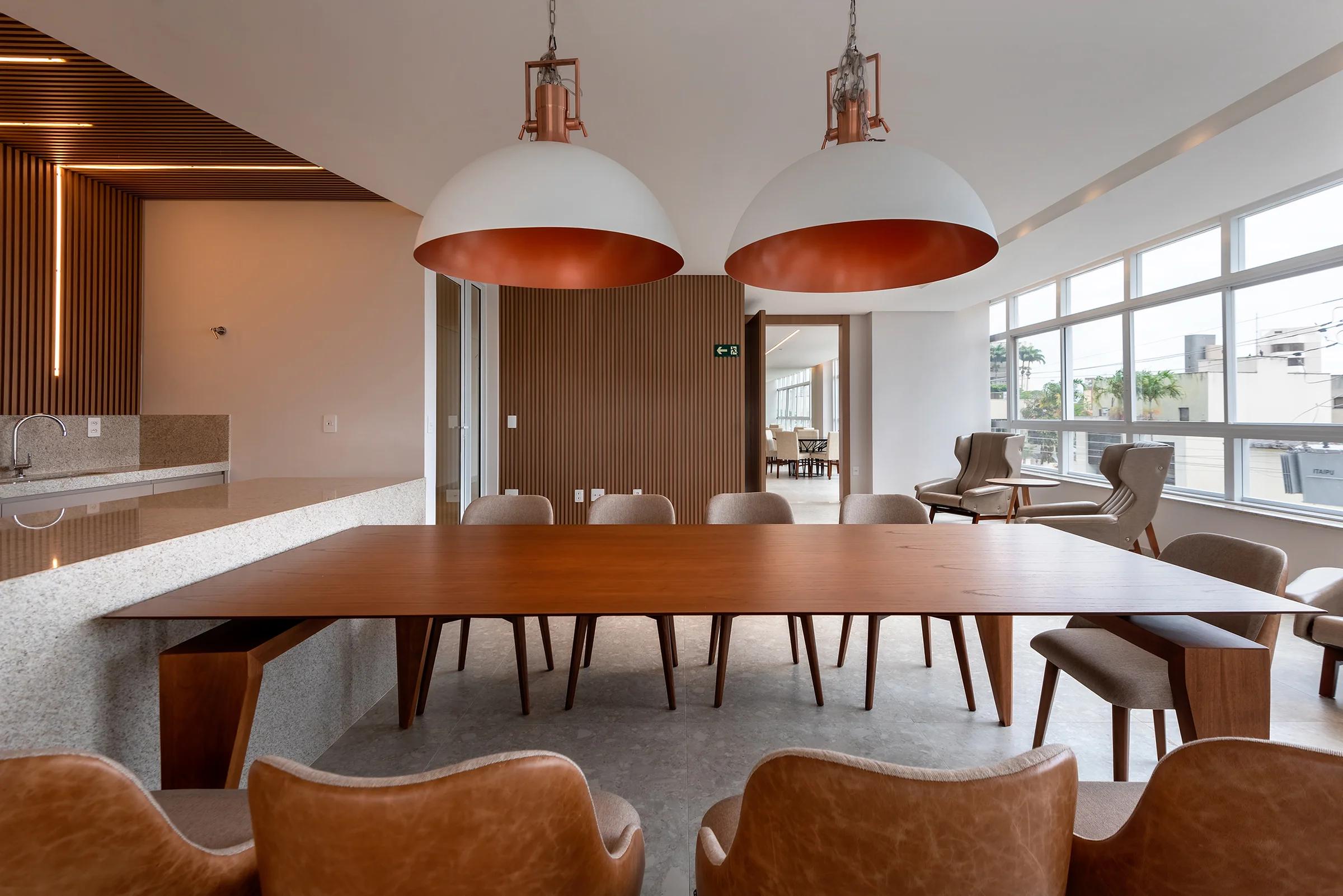 Mesa de jantar ampla com pendentes circulares em espaço gourmet integrado