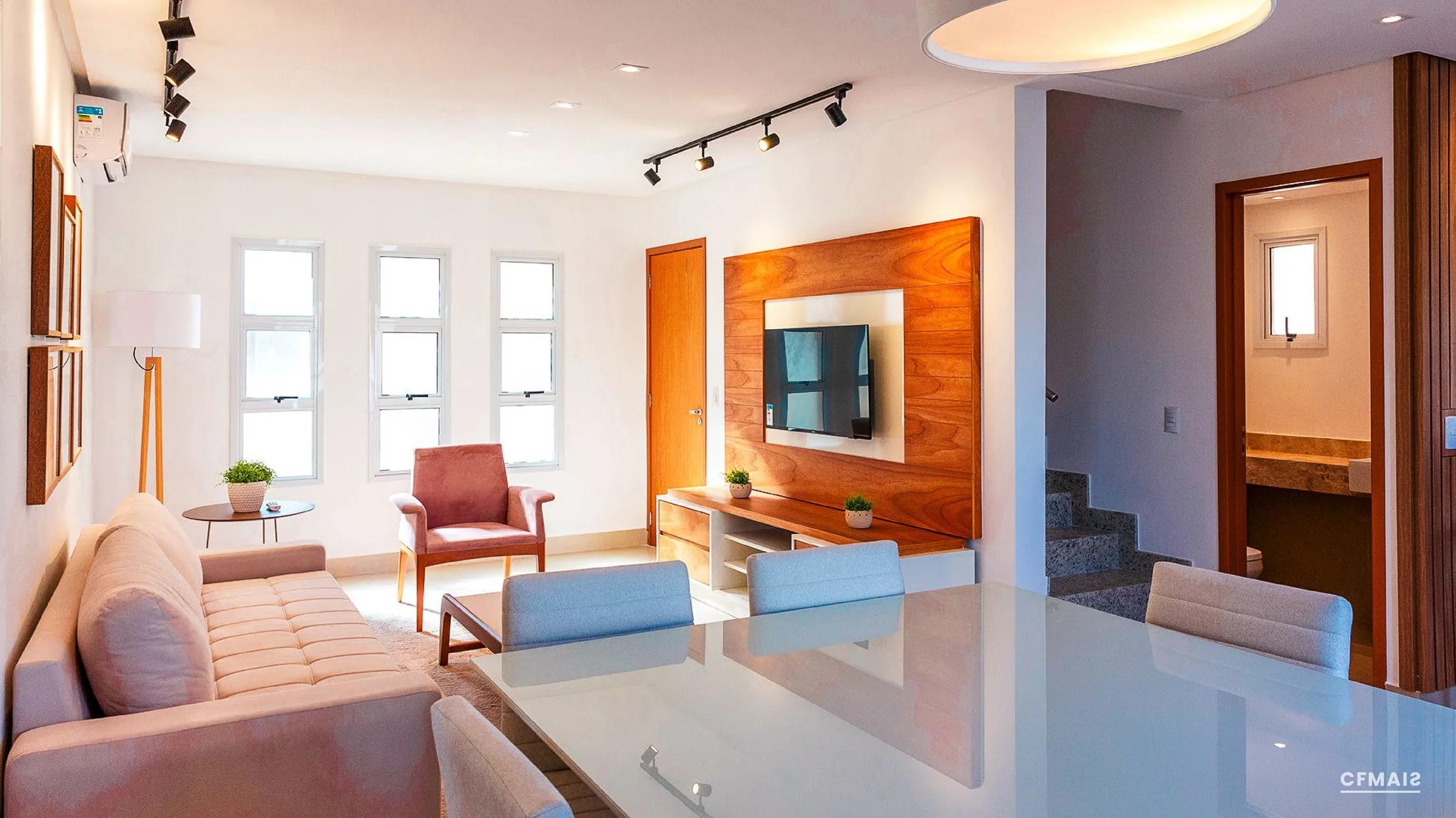 Living integrado com sala de estar, painel de TV e mesa de jantar