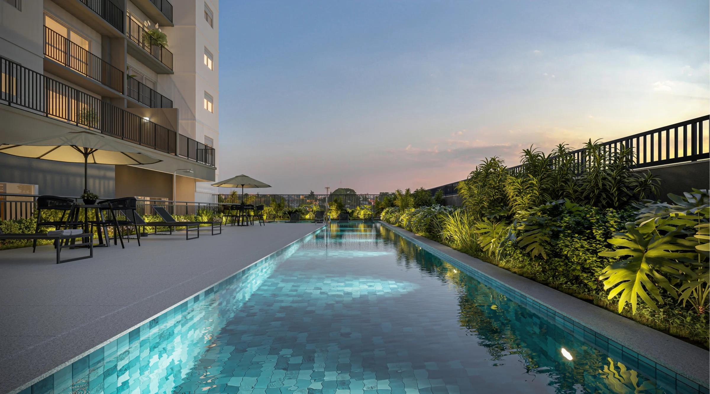 Piscina com raia, deck e paisagismo lateral ao entardecer