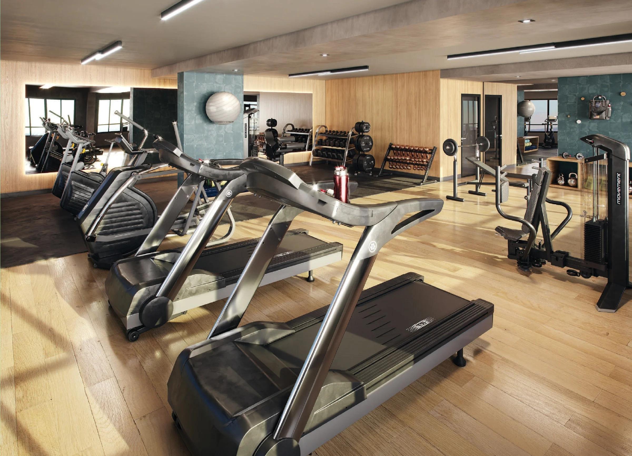 Academia equipada com esteiras, aparelhos de musculação e piso amadeirado