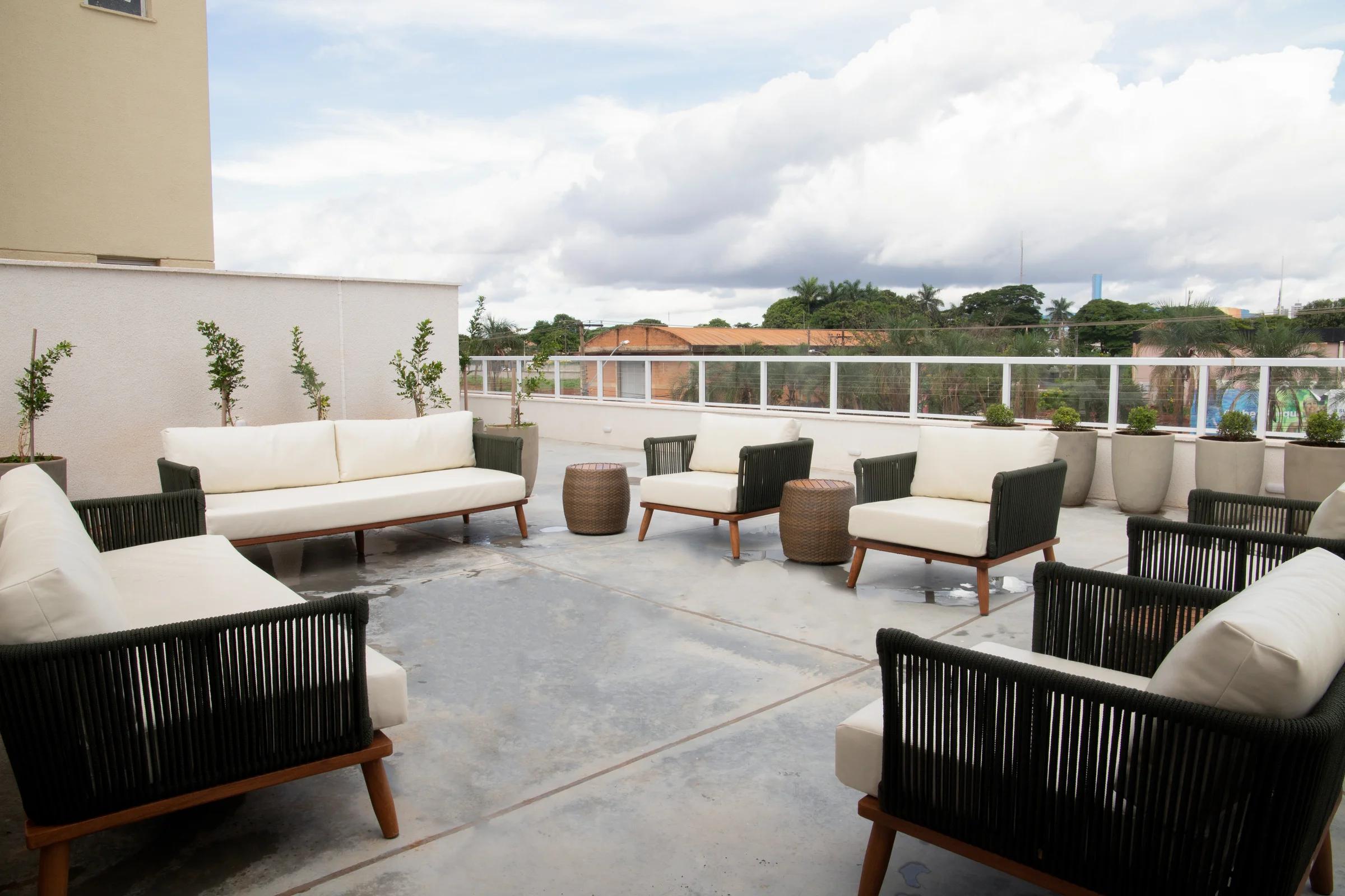 Terraço descoberto com sofás, poltronas e paisagismo