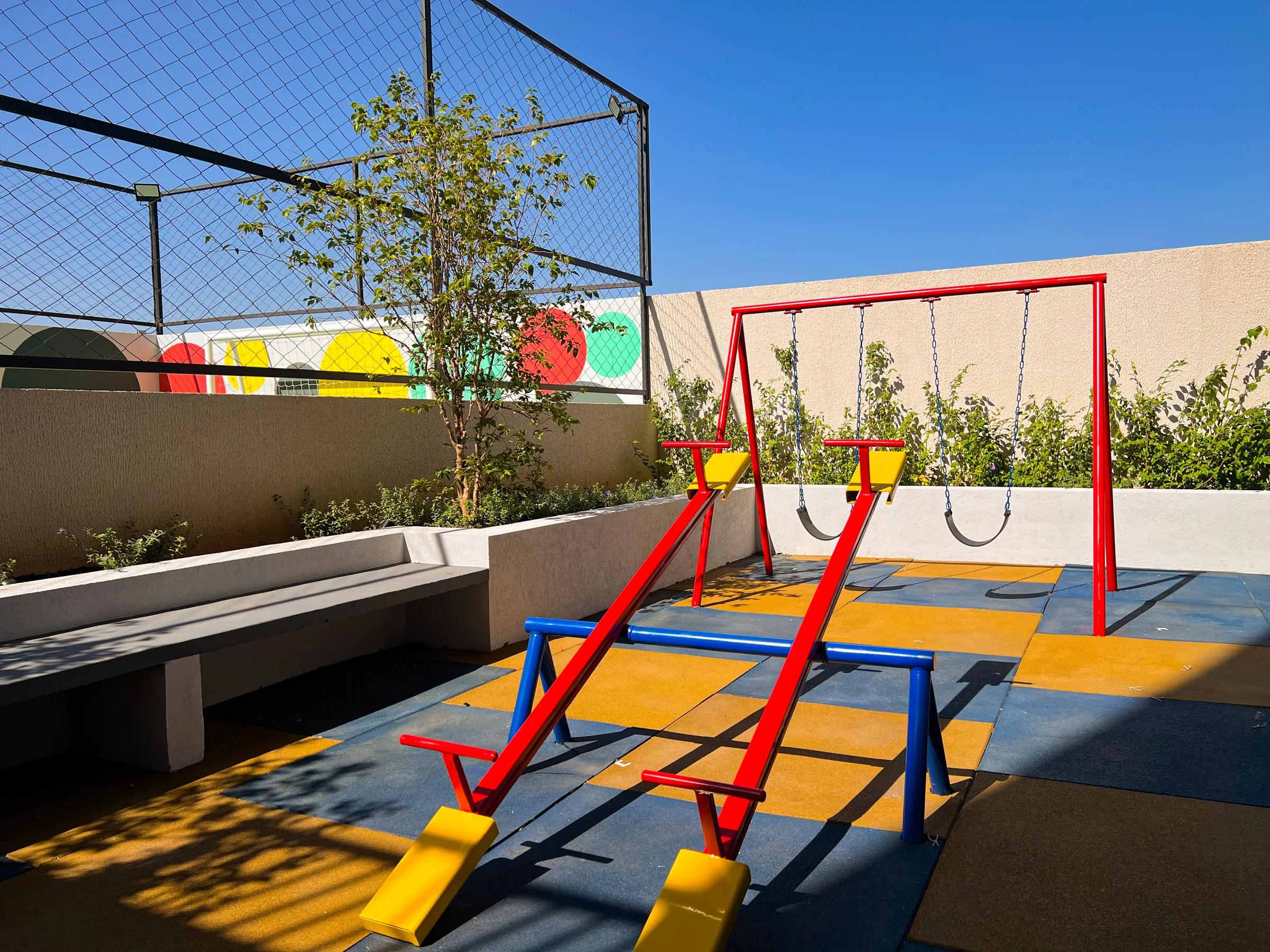 Foto do playground externo com balanços e escorregador