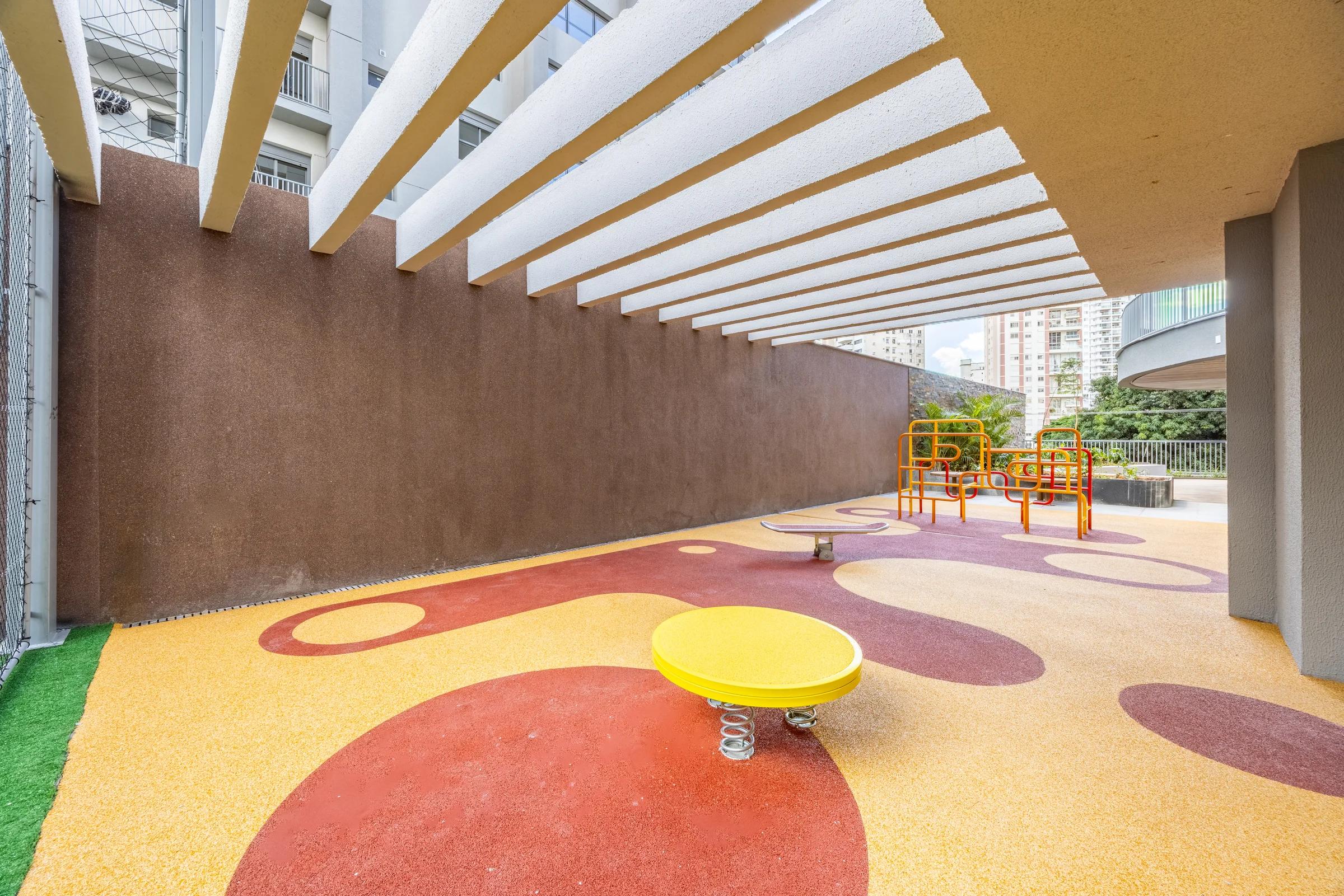 Perspectiva de espaço infantil com piso colorido e brinquedo baixo.